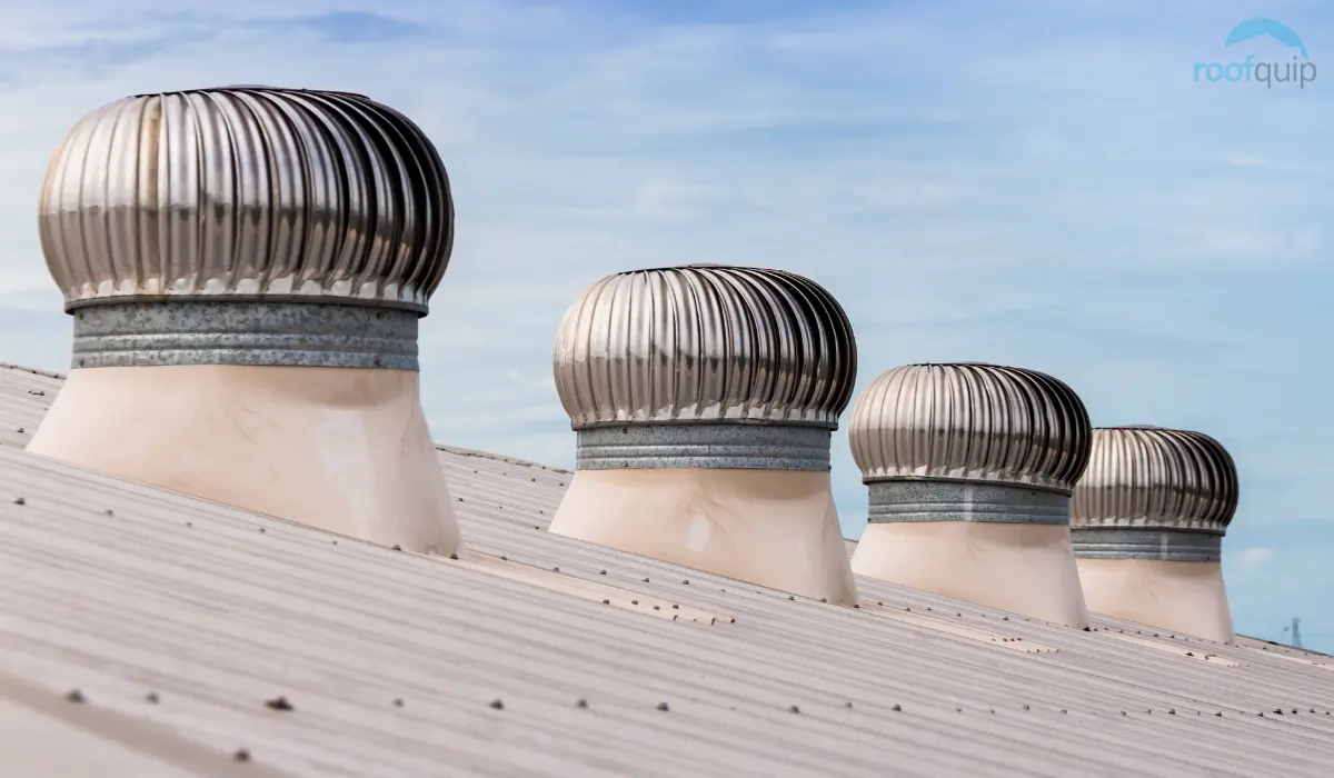 Multiple turbine ventilators installed on a sloped metal industrial roof.